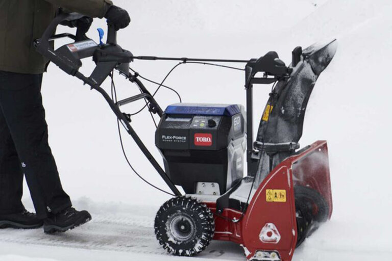 Close up, side view of Toro 60V SnowMaster snowblower on a snowy driveway