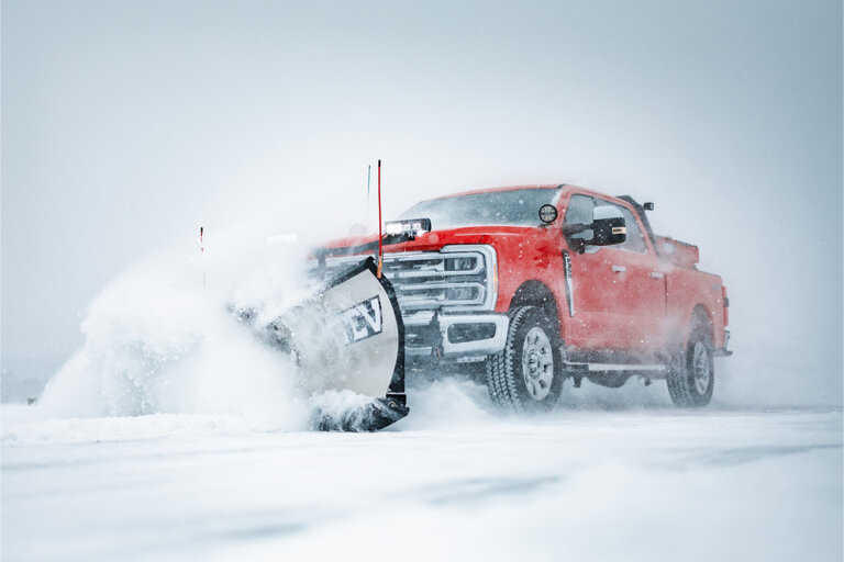 BOSS snow plow on front of a red pick up truck plowing snow