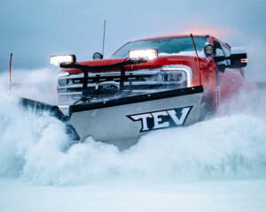 BOSS TEV snow plow on front of red pick up truck plowing snow