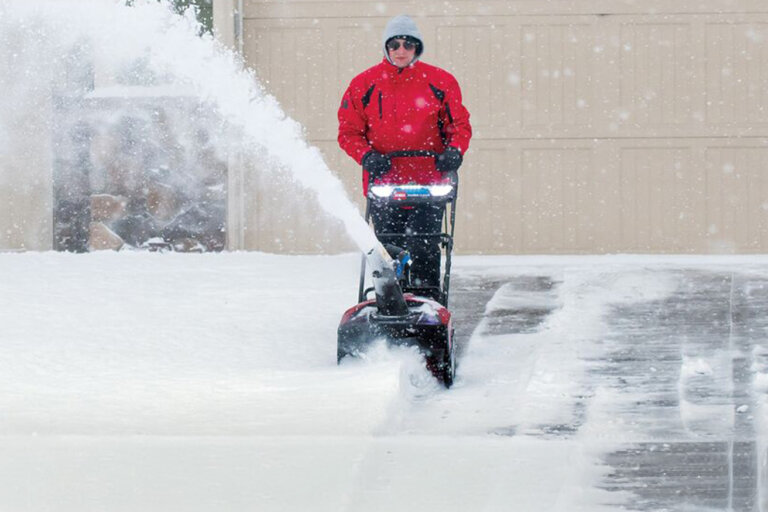 Woman clearing snowy driveway with Toro Power Clear snowblower