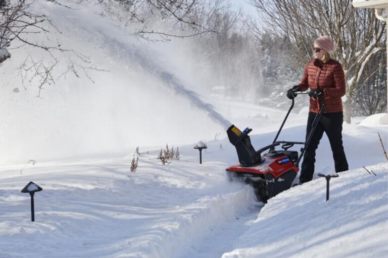 Woman clearing snow covered sidewalk with Toro Power Clear snow blower