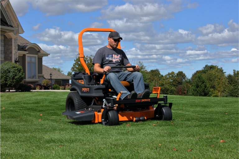 Man riding on a Scag Patriot zero turn mower cutting green grass