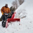Man behind a Toro power max snow blowers blowing large piles of snow
