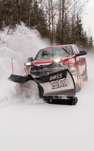 BOSS v-blade snow plow on the front of red pickup truck plowing snow