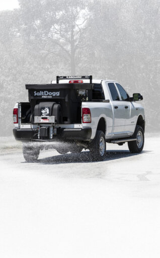 SaltDogg salt spreader on the back of a white pickup truck spreading salt on a icy road