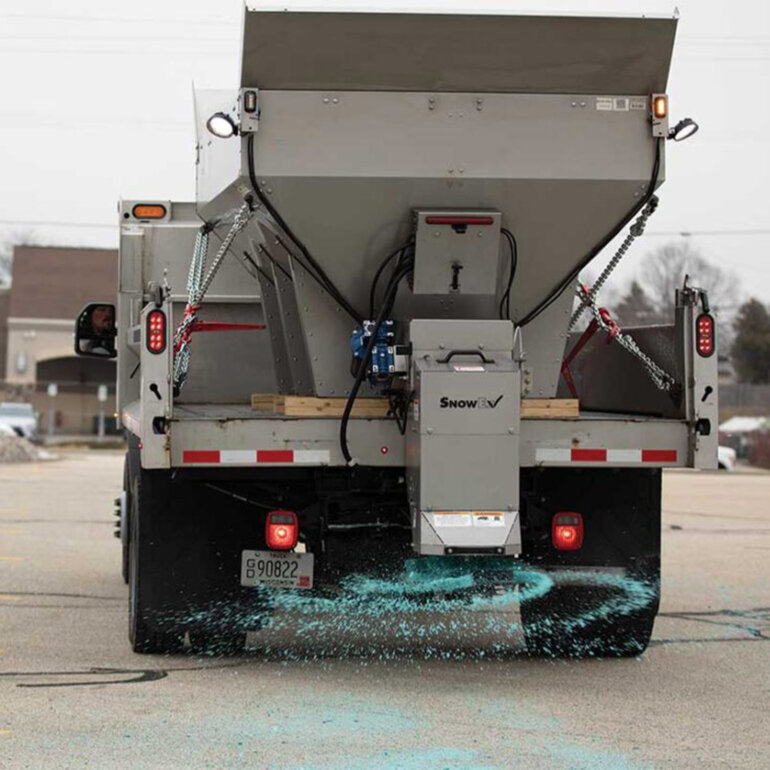 Snowex Renegade salt spreader in the bed of a large dump truck spreading salt