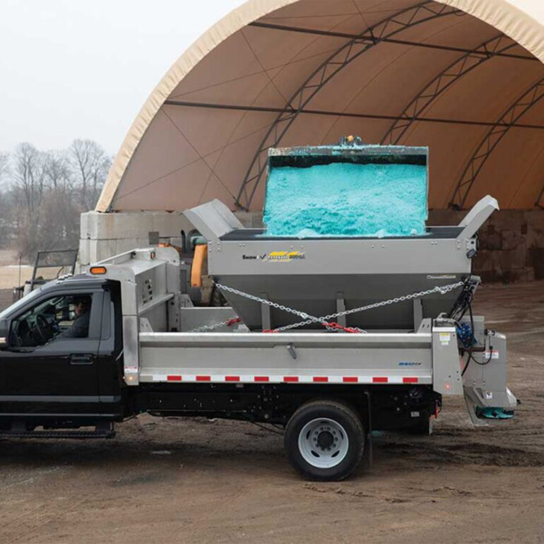 Salt being dumped into the hopper of a Snowex Renegade salts spreader