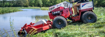 Ventrac tractor model 4520 mowing on a steep incline next to a pond