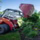 Vetnrac 4520 PRO tractor with power bucket attachment dumping mulch in a flower bed against a house