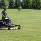 Man on a Scag V-Ride XL cutting grass in a large field