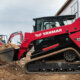 Man running a Yanmar TL100VS track loader with dirt in the bucket at a jobsite